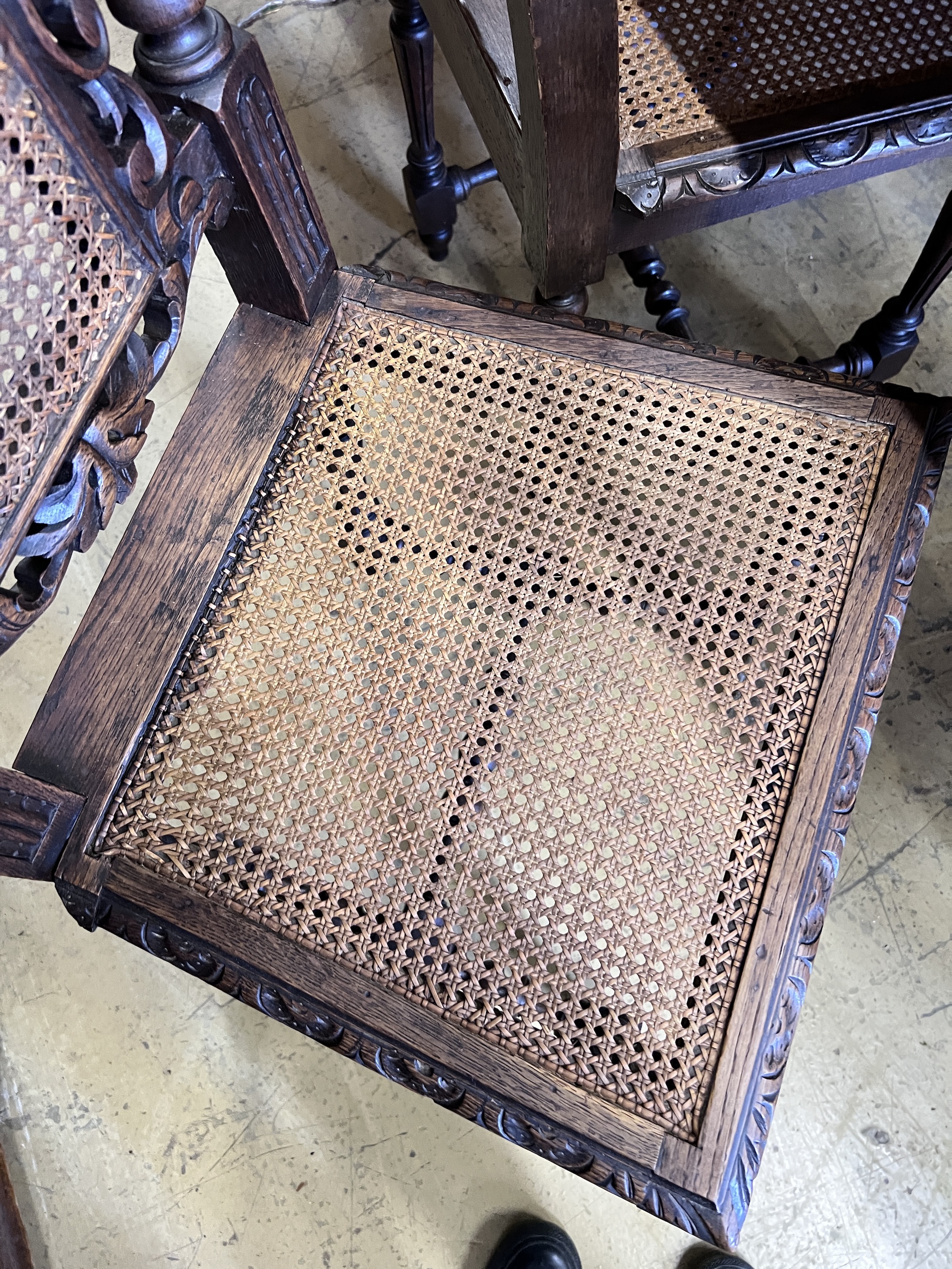 A set of four late 19th century Flemish style carved oak dining chairs with caned seats